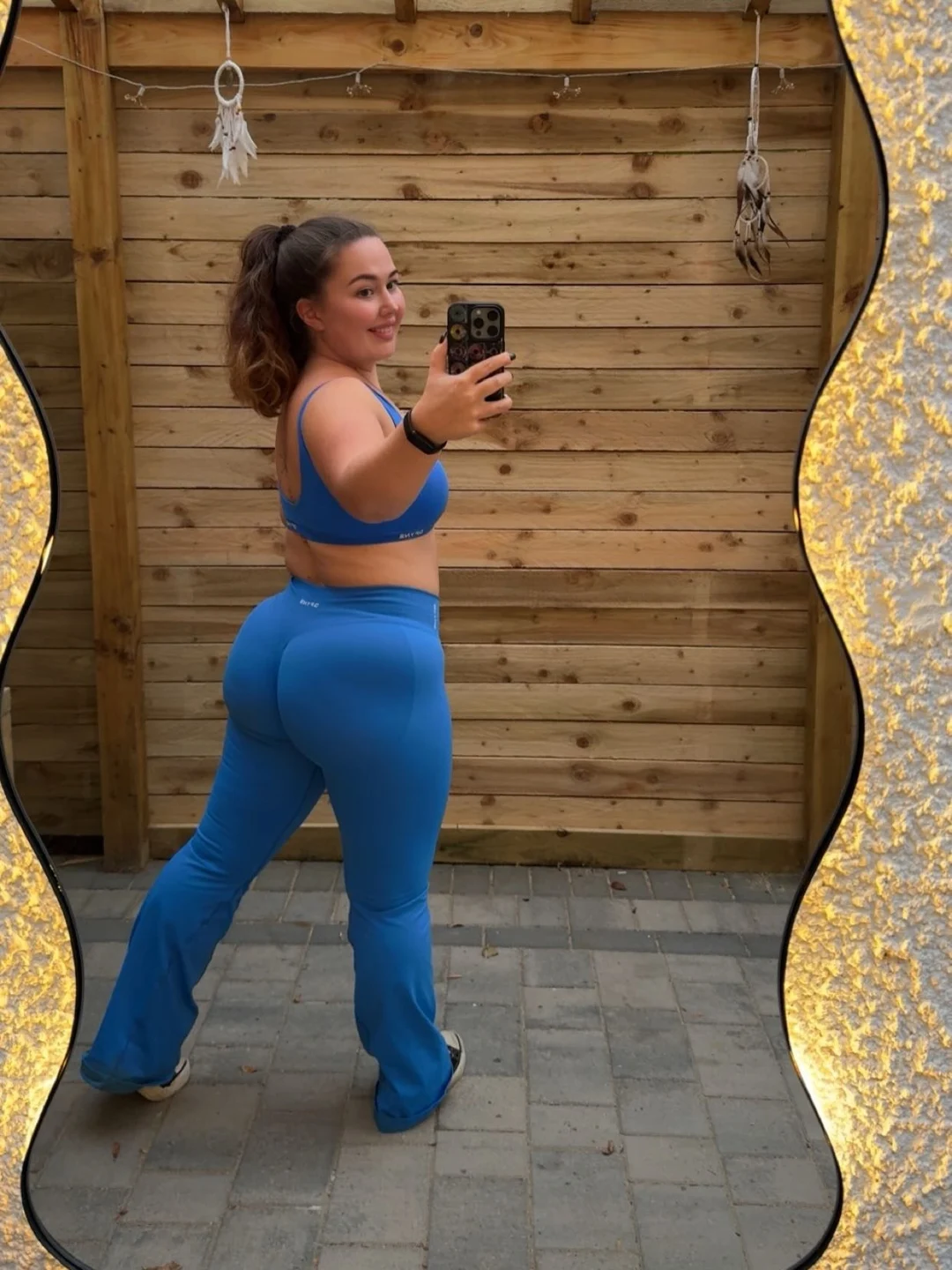 Em in blue gymwear taking a mirror photograph outdoors