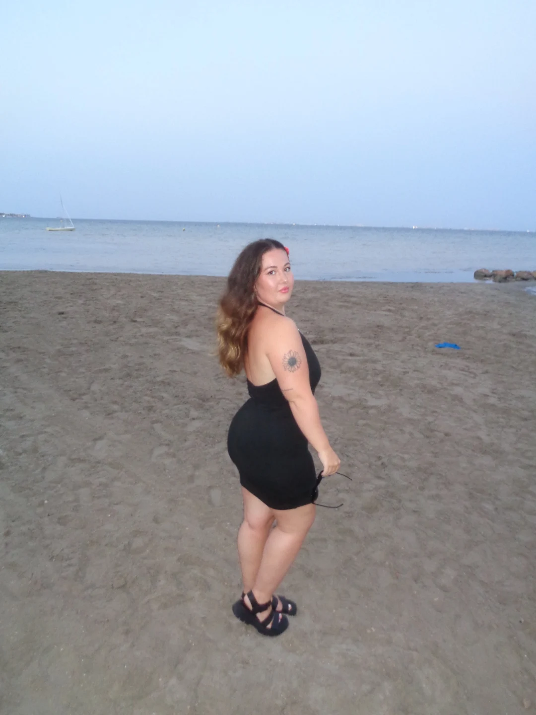 Em wearing a black outfit during a beach walk